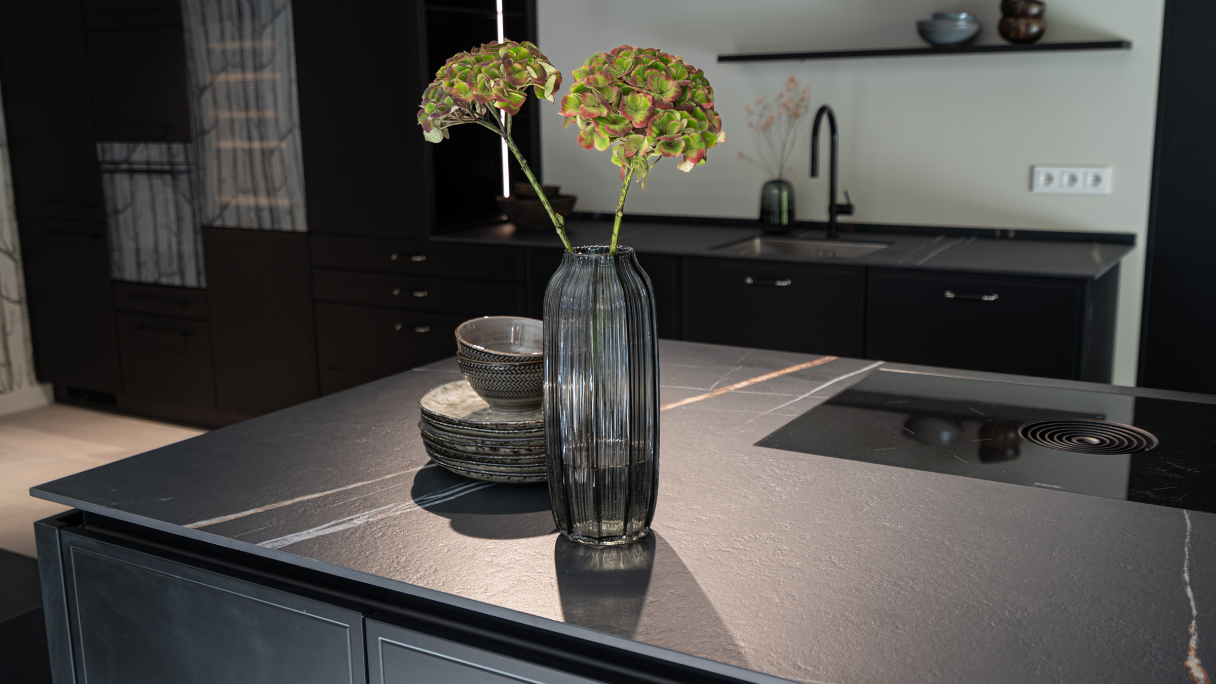 Kücheninsel mit schwarzer Keramikarbeitsplatte und Kochfeld